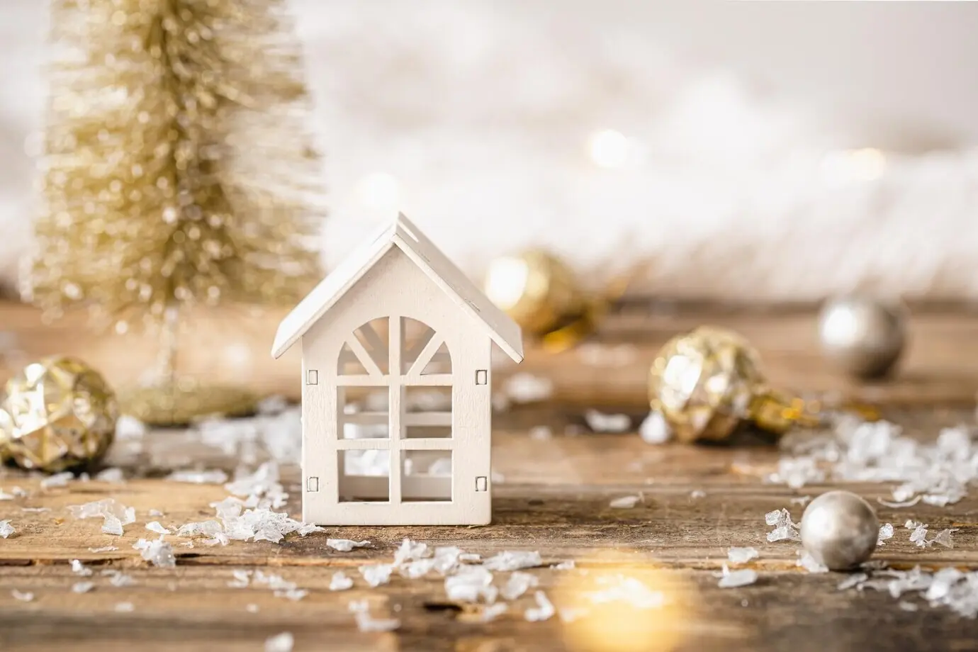 A small wooden house against a blurred Christmas bokeh background.